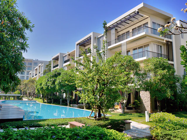 A pool among trees beside low-rise apartments